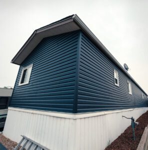 Corner view of a blue house with horizontal siding and a fisheye lens distortion effect.