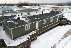 Snow-dusted modular home with a deck in a suburban setting.